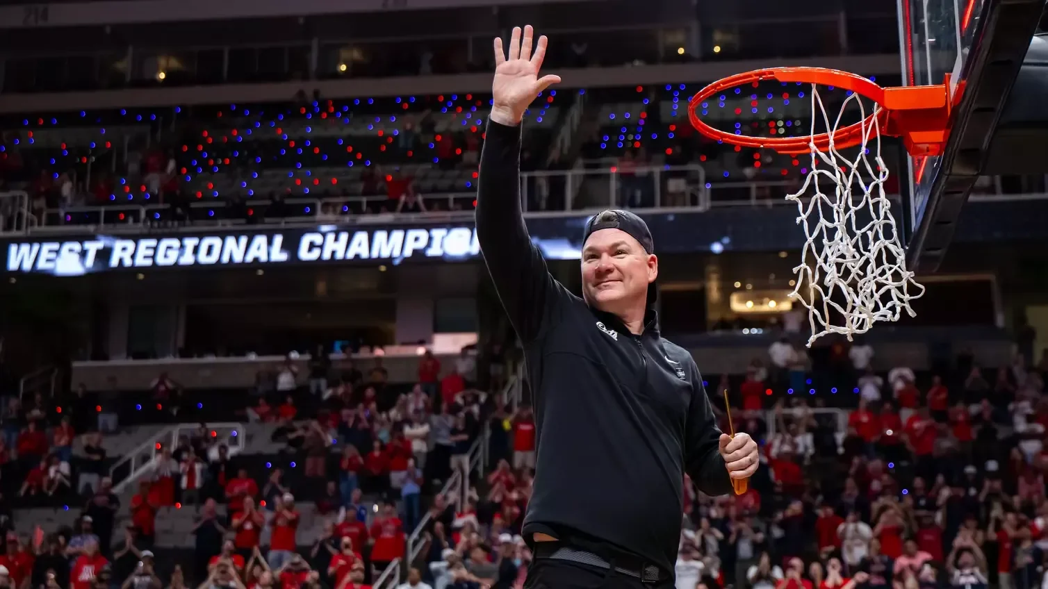 Tommy Lloyd waves beside the basketball hoop after Arizona's March 2026 regional final