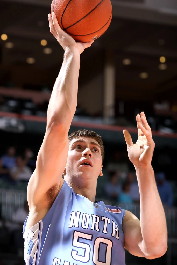 Tyler Hansbrough raises a basketball in his right hand while wearing a blue North Carolina number 50 jersey
