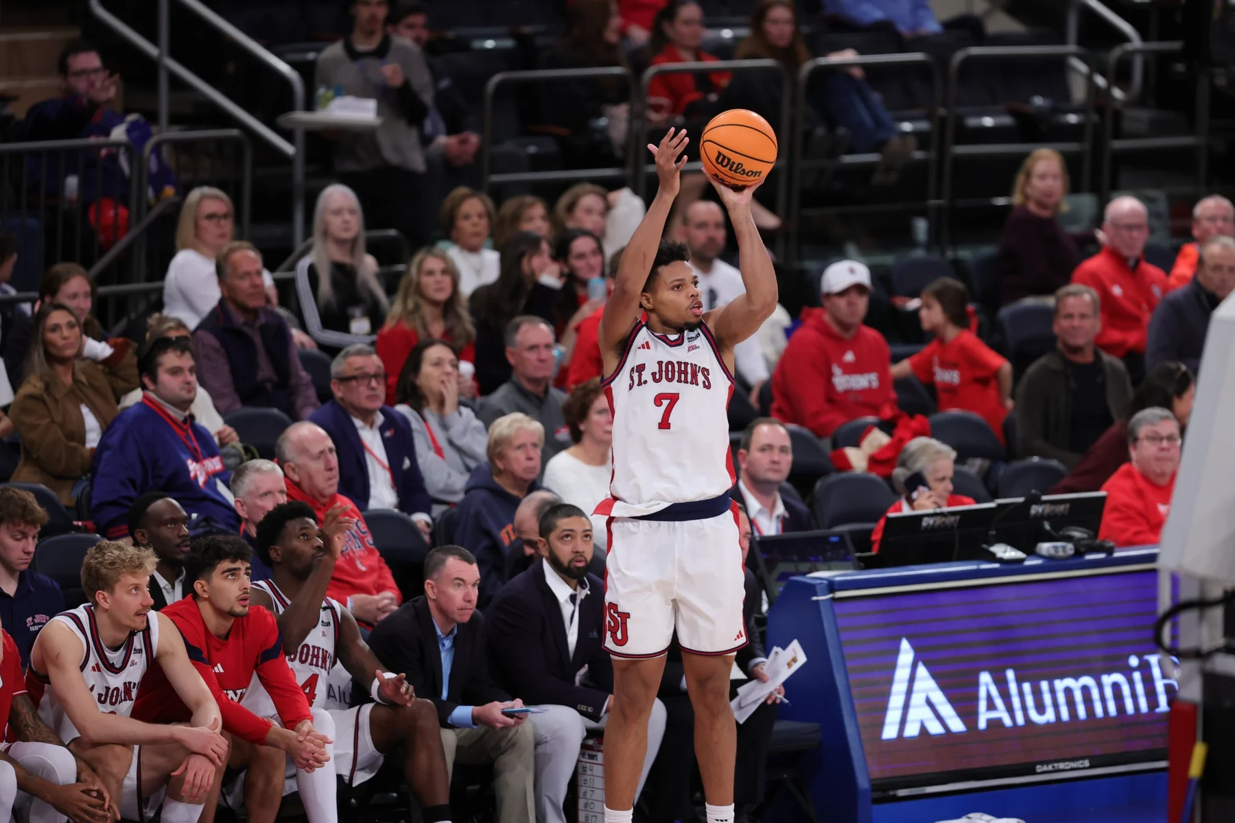 St. John's player rises for a jump shot beside the team bench