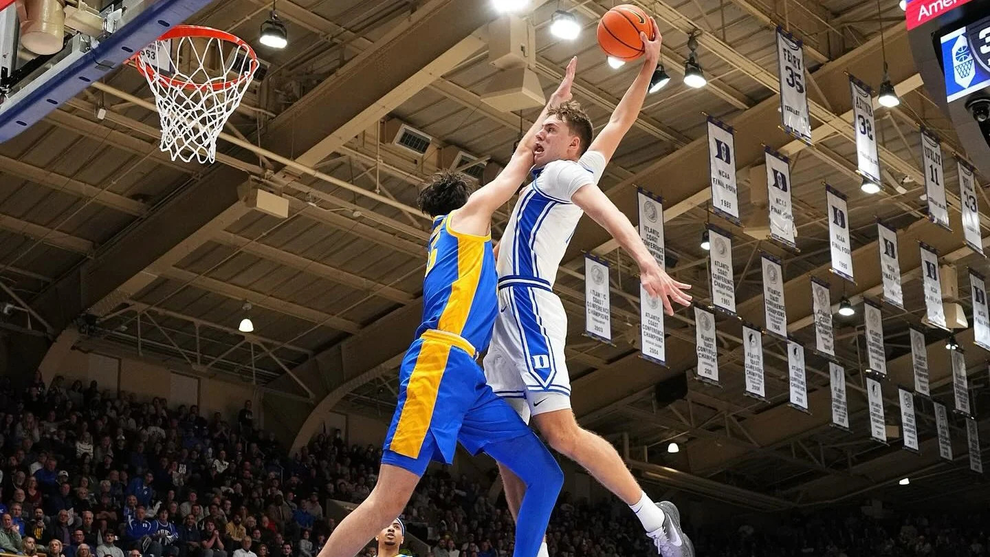 Cooper Flagg rises toward the rim over a blue-and-yellow defender