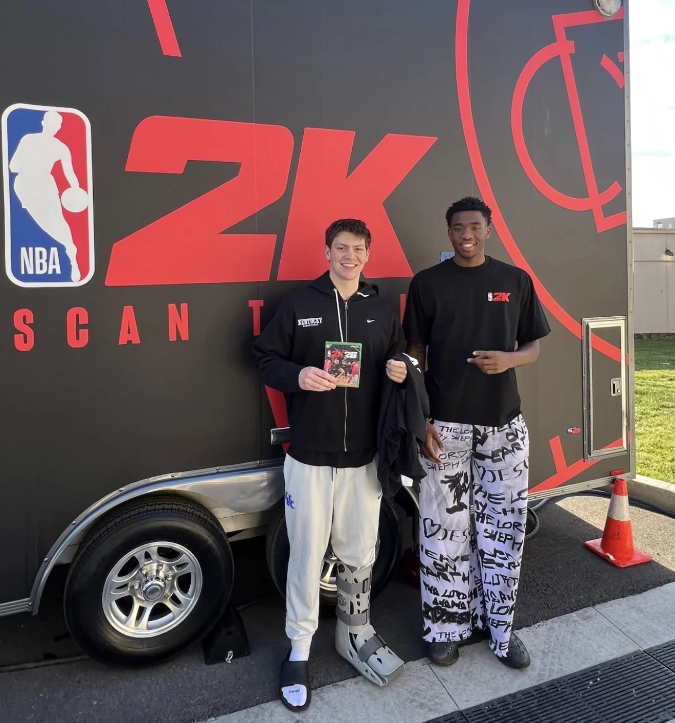 Two people beside a 2K Scan Truck, one holding an NBA 2K26 game case