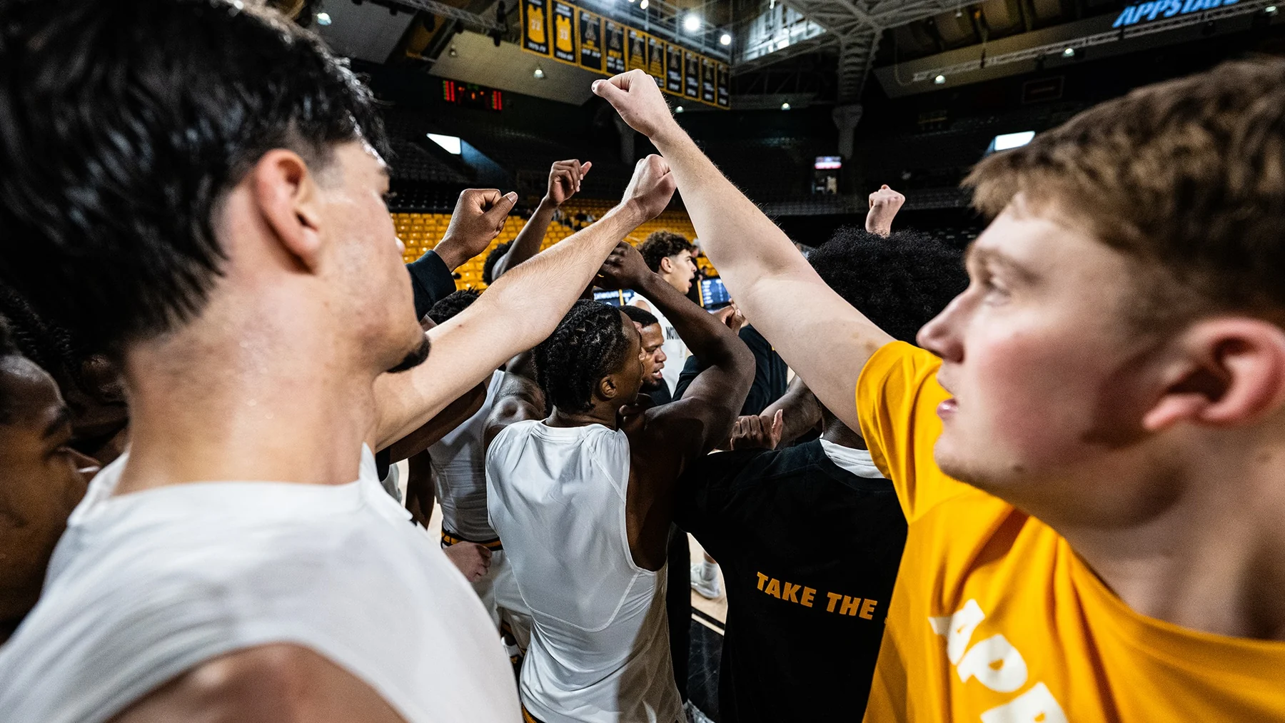 App State basketball players raising their hands together in a team huddle