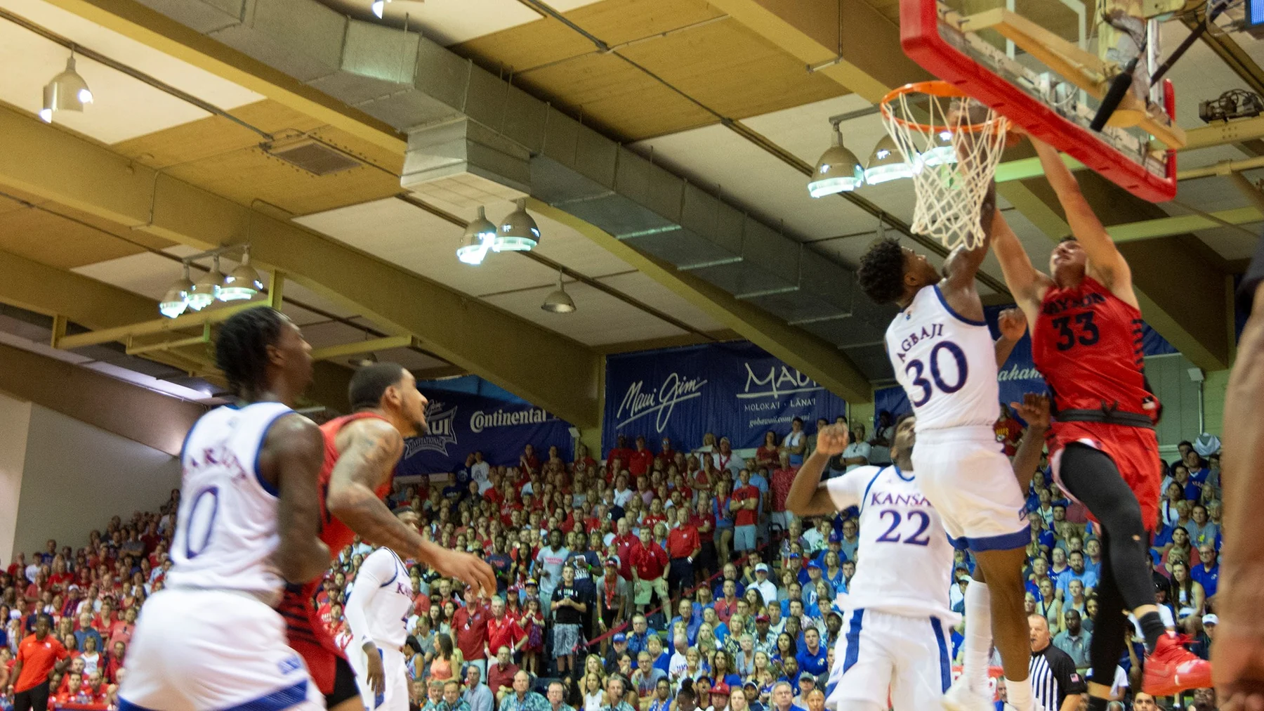 A Dayton player in red attempts a shot against Kansas defenders in white