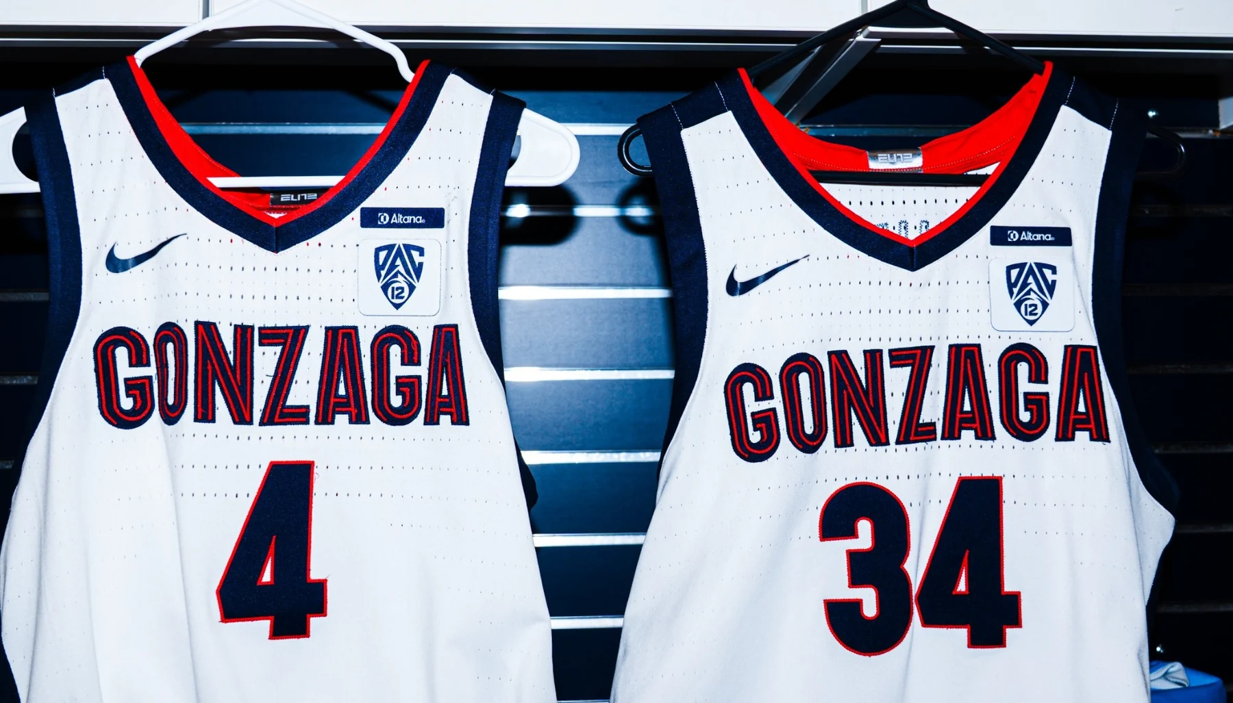 Two white Gonzaga jerseys on hangers with Altana, Pac-12 and Nike marks