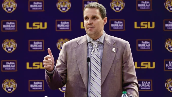 Will Wade speaks at a microphone in front of an LSU press-conference backdrop