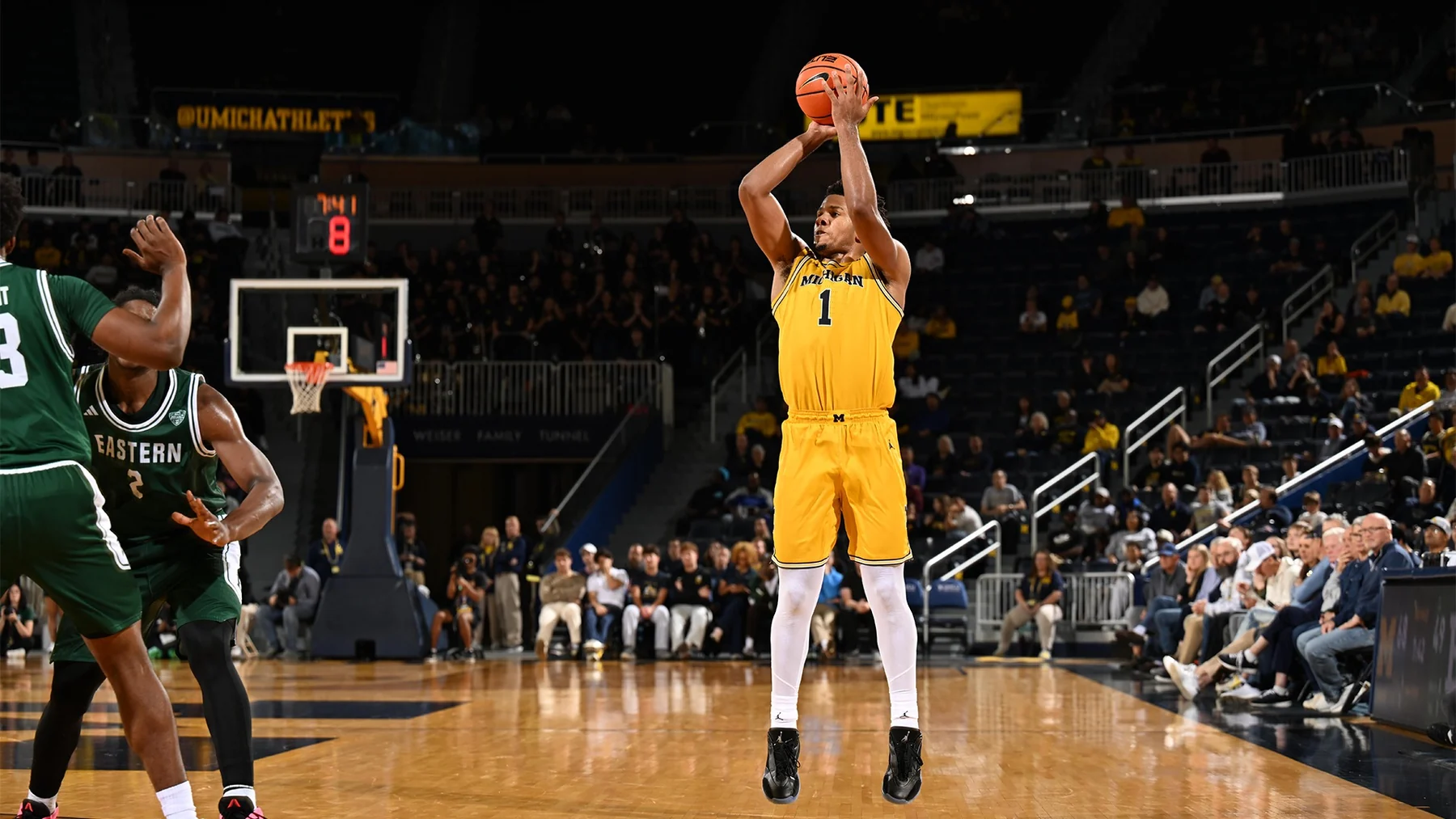 Trey McKenney shoots in a maize Michigan uniform against Eastern Michigan's green jerseys