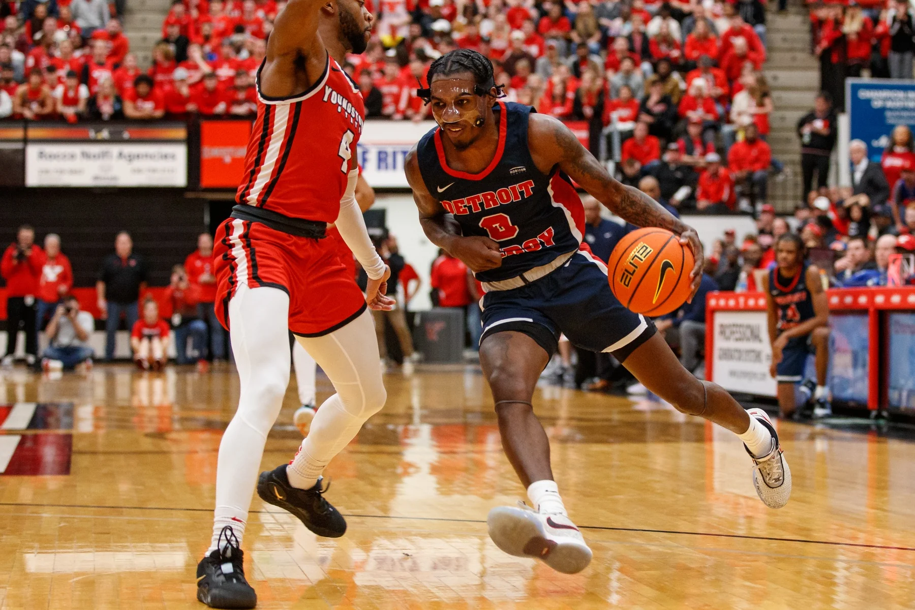 Antoine Davis drives past a Youngstown State defender in a dark Detroit Mercy uniform