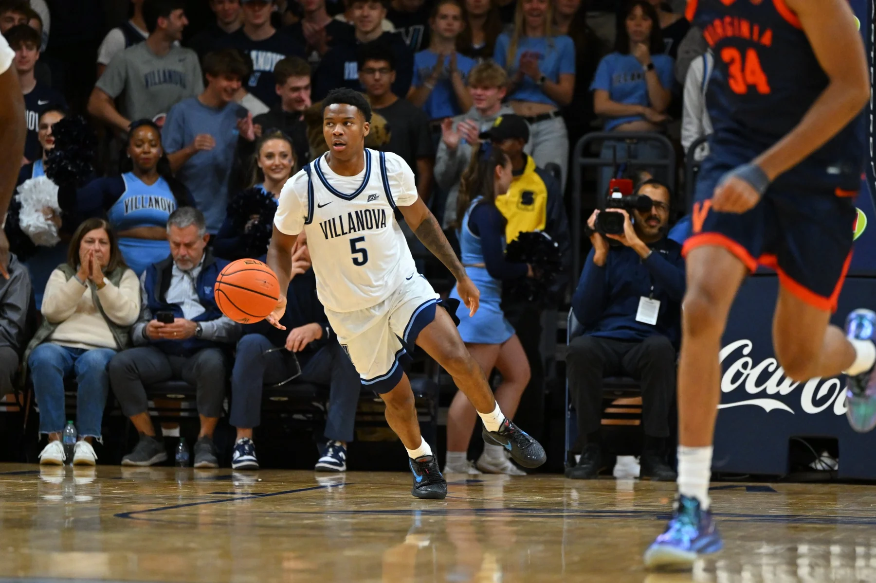 Villanova number five dribbling against Virginia with spectators behind the court