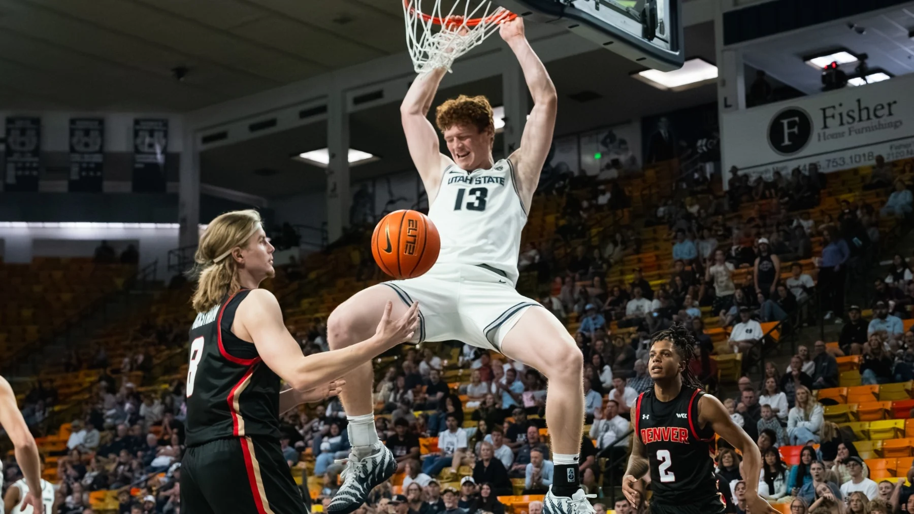 Utah State number thirteen finishing a dunk with Denver defenders beneath the basket