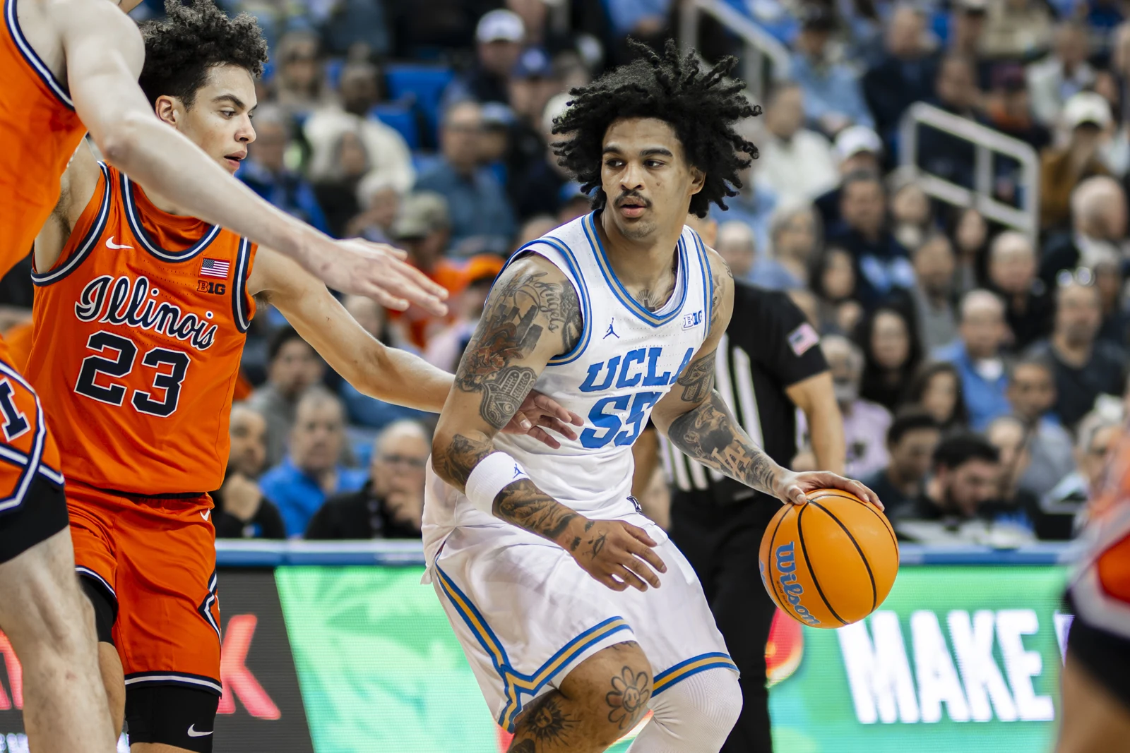 Skyy Clark in a white UCLA number55 jersey dribbling against an Illinois defender