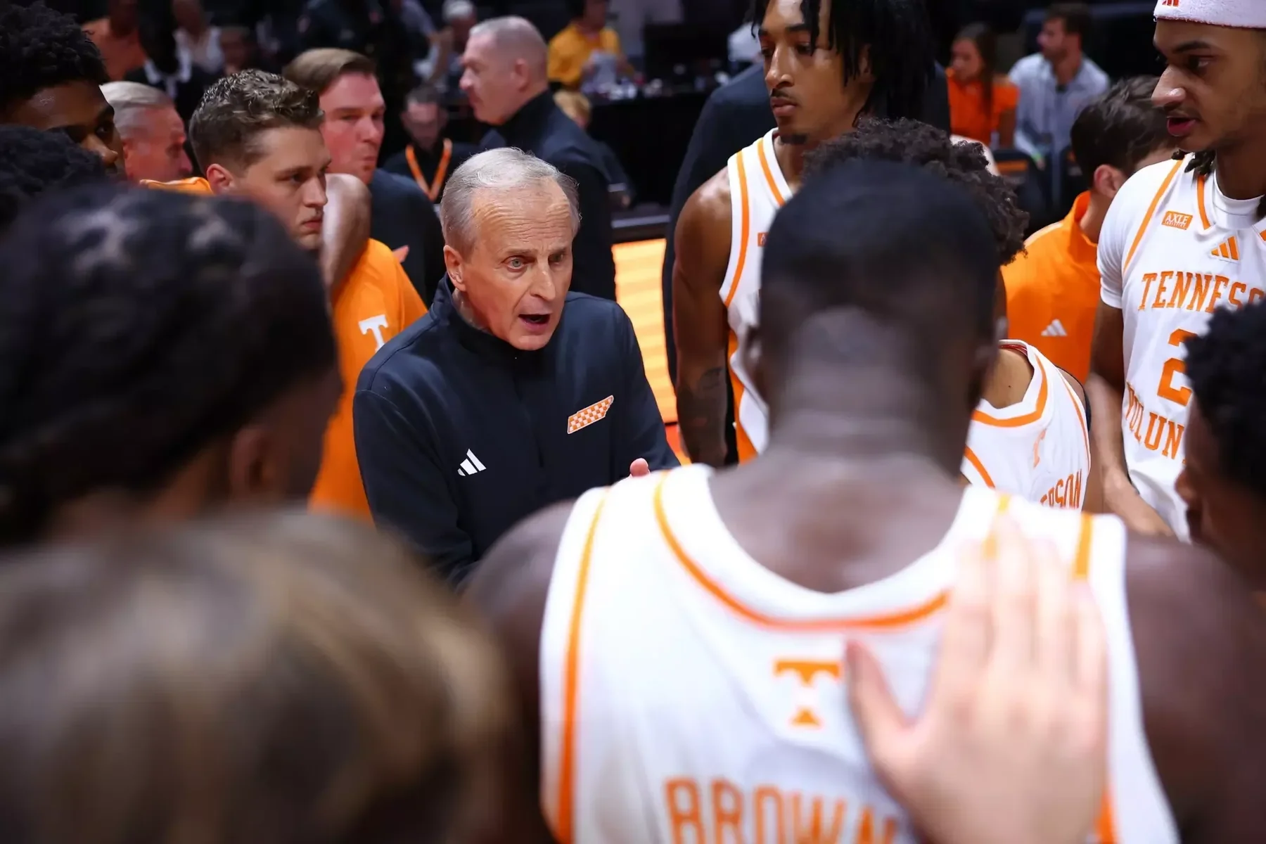 Tennessee coach addressing players gathered in a courtside huddle