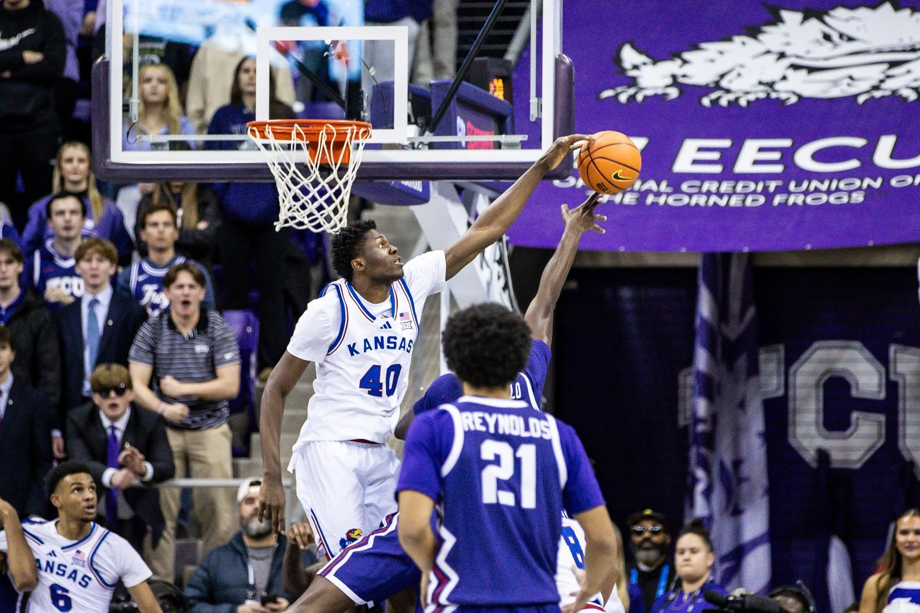 Flory Bidunga in a white Kansas jersey contests a TCU shot near the basket