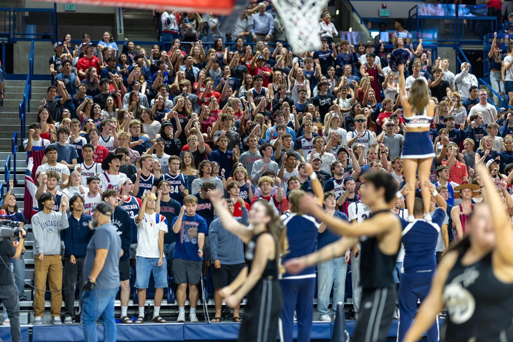 Gonzaga supporters stand behind the basket with cheerleaders in the foreground